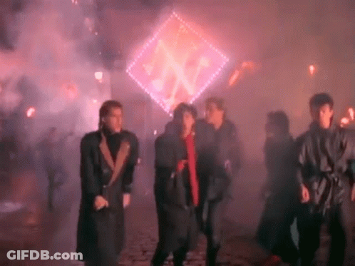 A Group Of People Are Dancing In Front Of A Glowing Sign . GIF