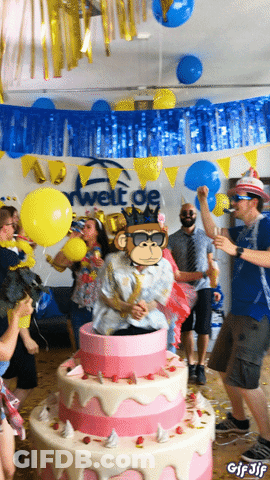 A Group Of People Are Dancing In Front Of A Large Cake With A Monkey On It GIF