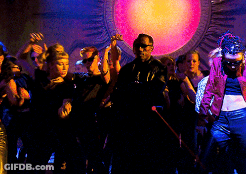 A Group Of People Are Dancing In Front Of A Large Pink Light GIF