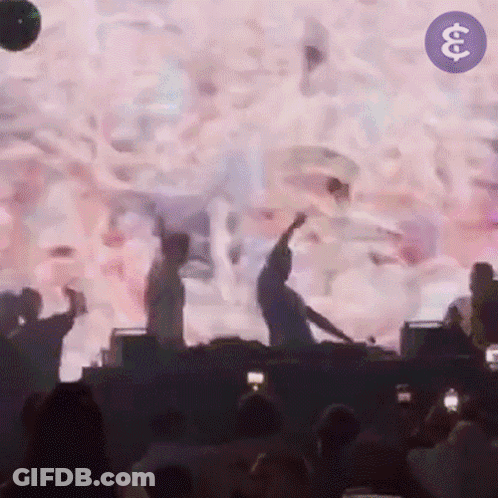 A Group Of People Are Dancing In Front Of A Large Screen With The Letter S On It GIF