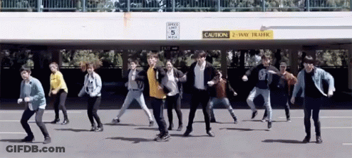 A Group Of People Are Dancing In Front Of A Sign That Says " Caution 2 Way Traffic " GIF