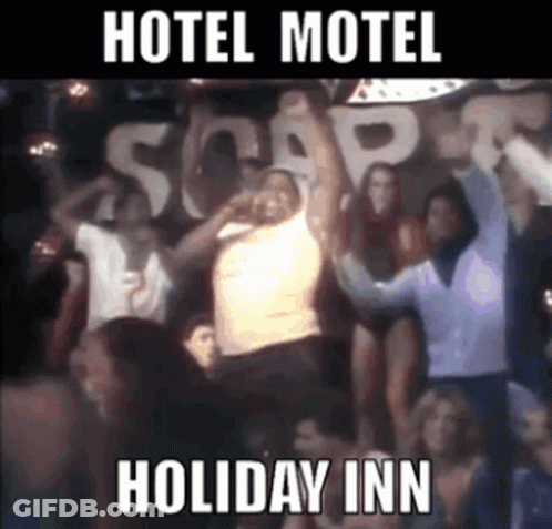 A Group Of People Are Dancing In Front Of A Sign That Says " Hotel Motel Holiday Inn " GIF