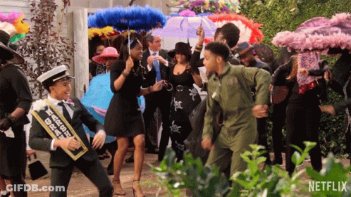 A Group Of People Are Dancing In Front Of A Sign That Says Netflix On It GIF