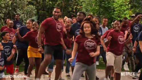 A Group Of People Are Dancing In Front Of A Sign That Says Netflix On It GIF