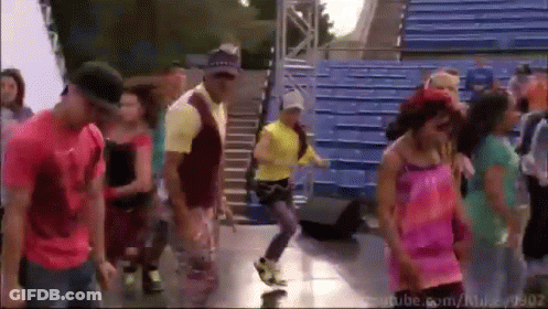 A Group Of People Are Dancing In Front Of Blue Bleachers With Youtube.com In The Bottom Right Corner GIF