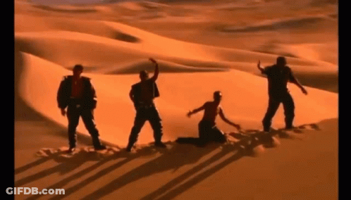 A Group Of People Are Dancing In The Desert . GIF