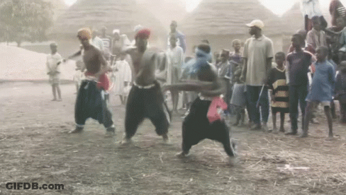 A Group Of People Are Dancing In The Dirt In Front Of A Crowd GIF