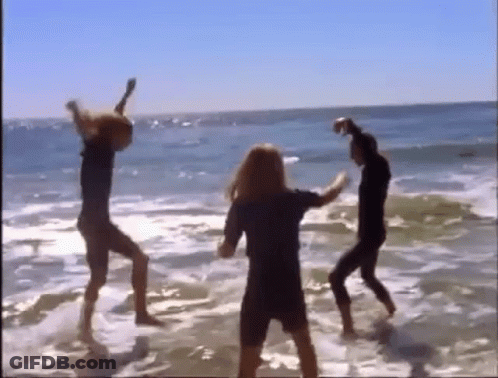 A Group Of People Are Dancing In The Water On A Beach GIF