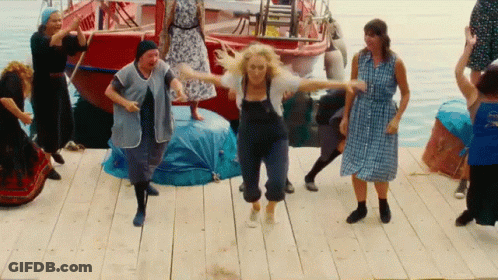 A Group Of People Are Dancing On A Dock With A Boat In The Background GIF