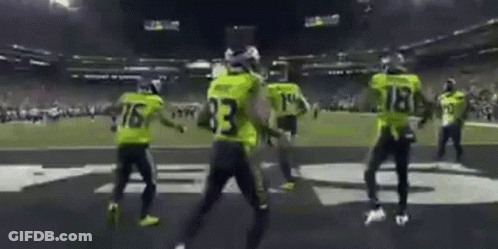 A Group Of People Are Dancing On A Football Field . GIF