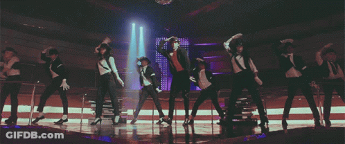 A Group Of People Are Dancing On A Stage In A Dark Room GIF