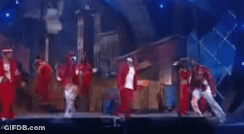 A Group Of People Are Dancing On A Stage In Front Of A Blue Background . GIF