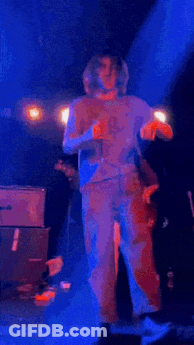A Group Of People Are Dancing On A Stage In Front Of A Blue Light GIF