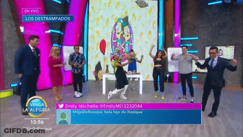 A Group Of People Are Dancing On A Stage In Front Of A Sign That Says En Vivo GIF