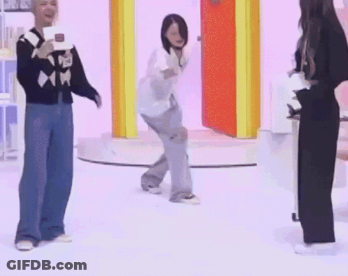 A Group Of People Are Dancing On A Stage While A Man Holds A Microphone . GIF