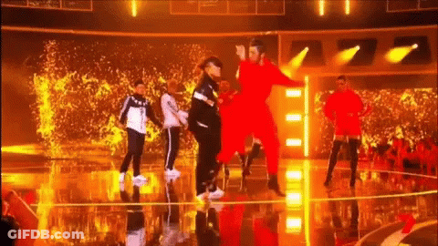 A Group Of People Are Dancing On A Stage With A Crowd Watching . GIF