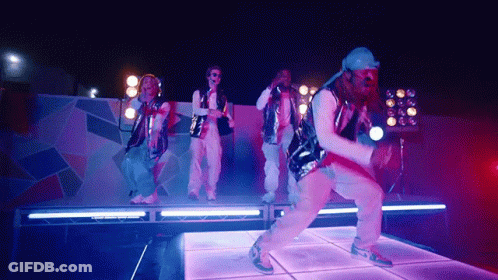 A Group Of People Are Dancing On A Stage With Purple Lights Behind Them GIF