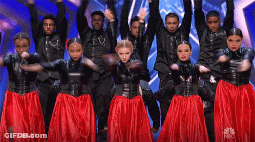 A Group Of People Are Dancing On A Stage With Their Arms In The Air GIF