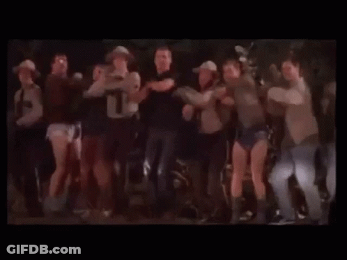 A Group Of People Are Dancing Together On A Stage In A Dark Room . GIF