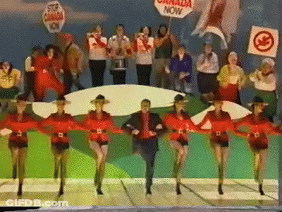 A Group Of People Are Dancing With A Sign That Says Canada Now GIF