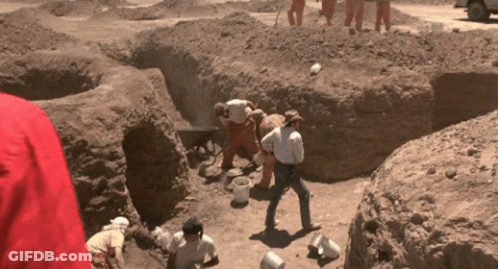 A Group Of People Are Digging In A Dirt Area GIF