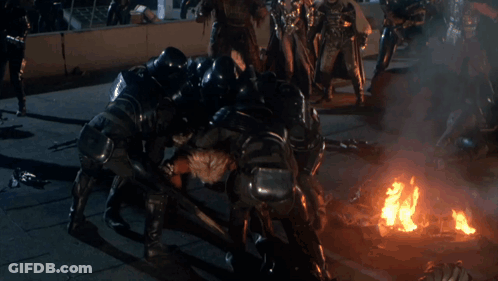 A Group Of People Are Fighting A Man In A Costume GIF