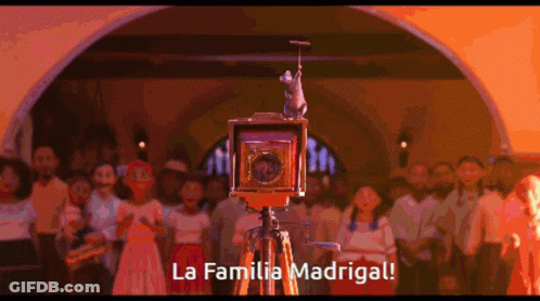 A Group Of People Are Gathered Around A Camera That Says La Familia Madrigal On It GIF
