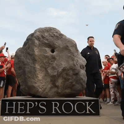 A Group Of People Are Gathered Around A Large Rock Called Hep 'S Rock GIF