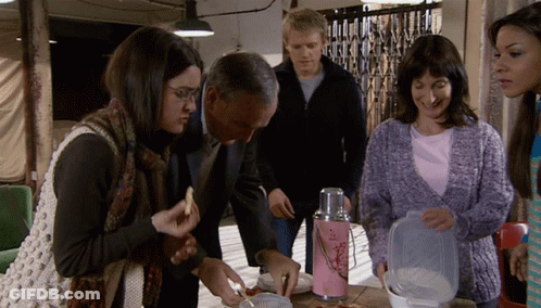 A Group Of People Are Gathered Around A Table With A Pink Thermos With Flowers On It GIF