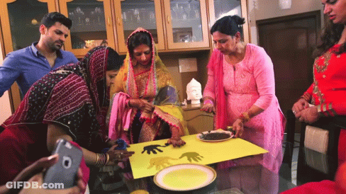 A Group Of People Are Gathered Around A Table With Plates And A Cell Phone GIF