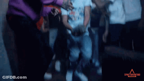 A Group Of People Are Gathered In A Dark Room With Spike Tarantino Written On The Bottom Right GIF