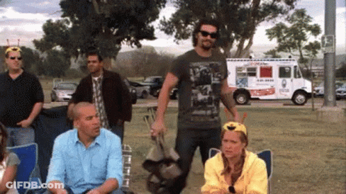 A Group Of People Are Gathered In A Park With An Ice Cream Truck Parked Behind Them GIF