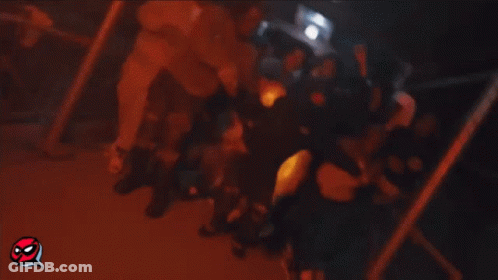 A Group Of People Are Gathered In A Room And One Of Them Is Wearing A Hooded Sweatshirt . GIF