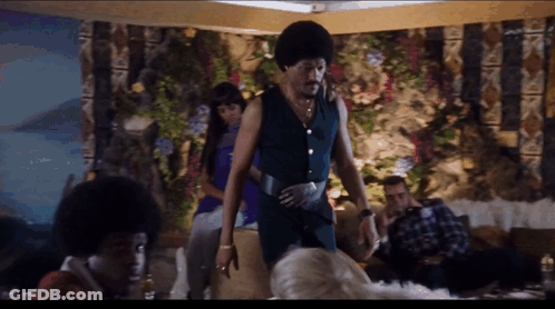 A Group Of People Are Gathered In A Room Including A Man In A Blue Outfit GIF