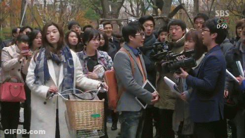 A Group Of People Are Gathered In Front Of A Sbs Sign GIF