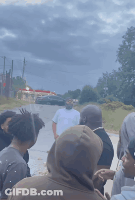 A Group Of People Are Gathered On The Side Of A Road GIF