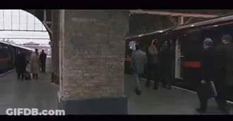 A Group Of People Are Getting On A Train At A Train Station GIF