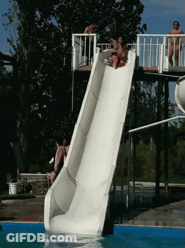 A Group Of People Are Going Down A Slide In A Pool GIF