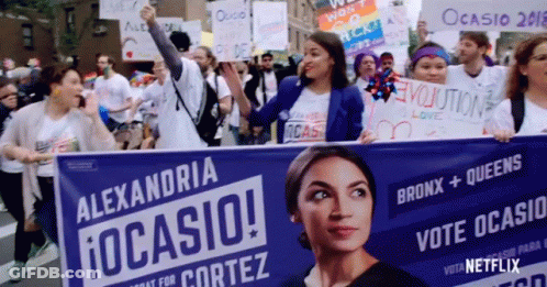 A Group Of People Are Holding A Banner That Says Alexandria Ocasio GIF