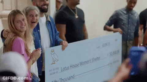 A Group Of People Are Holding A Large Check For Lotus House Women 'S Shelter . GIF
