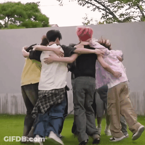 A Group Of People Are Hugging Each Other In A Huddle GIF