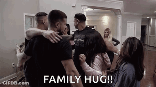 A Group Of People Are Hugging In A Living Room . GIF