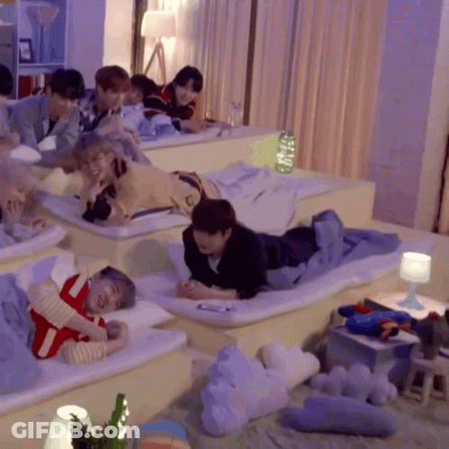 A Group Of People Are Laying On Mattresses In A Room With Purple Curtains GIF