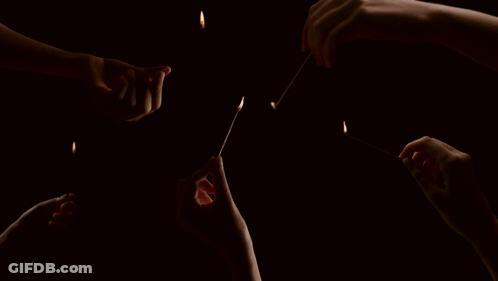 A Group Of People Are Lighting Matches In The Dark GIF
