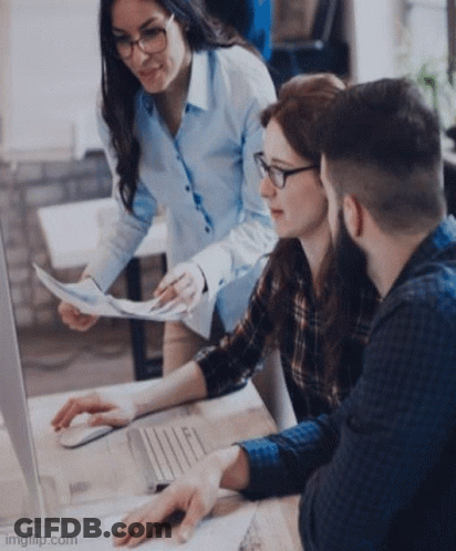A Group Of People Are Looking At A Computer Screen While A Woman Holds A Piece Of Paper . GIF