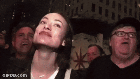 A Group Of People Are Looking Up At Something In A Dark Room GIF