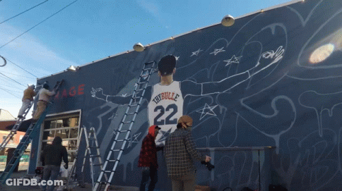 A Group Of People Are Painting A Mural Of A Man With The Number 22 On His Shirt GIF