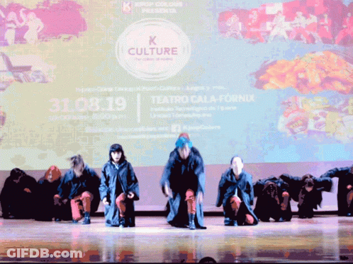 A Group Of People Are Performing On A Stage In Front Of A Large Screen That Says K Culture GIF