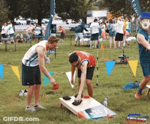 A Group Of People Are Playing A Game In A Park With A Sign That Says Giant GIF