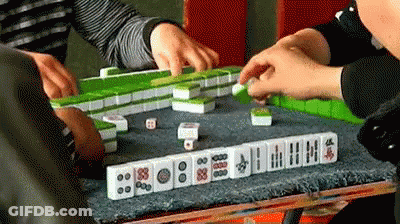 A Group Of People Are Playing A Game Of Mahjong With Dice . GIF